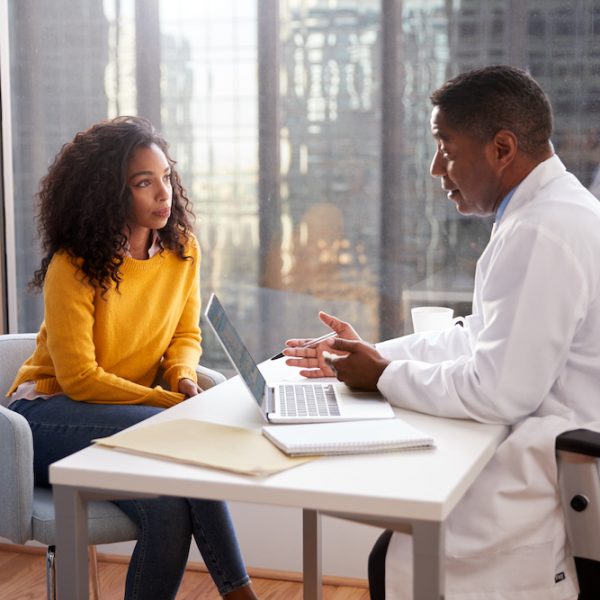 Serious Woman Having Consultation With Male Doctor In Hospital Office