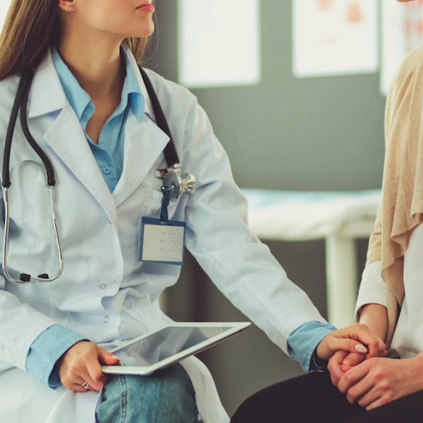 Doctor and patient discussing something while sitting at the table . Medicine and health care concept